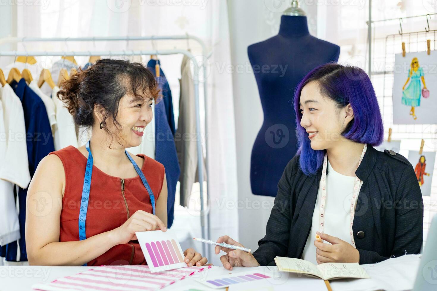 Team of fashionable freelance dressmakers choosing design and pantone for new custom made dress while working in artistic workshop studio for fashion design and clothing business industry photo