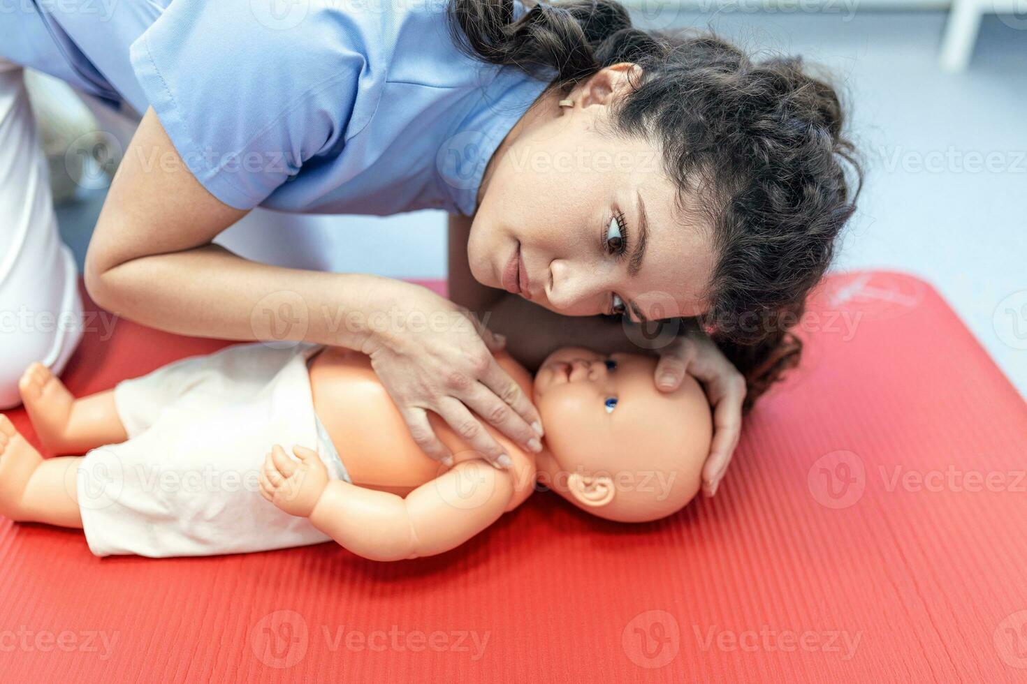 CPR practitioner examining airway passages on infant dummy. Model dummy lays on table and two doctors practice first aid. photo