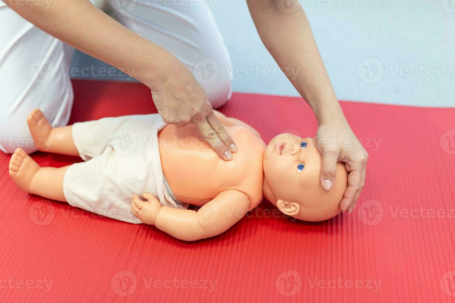Woman performing CPR on baby training doll with one hand compression. First Aid Training - Cardiopulmonary resuscitation. First aid course on cpr dummy. photo