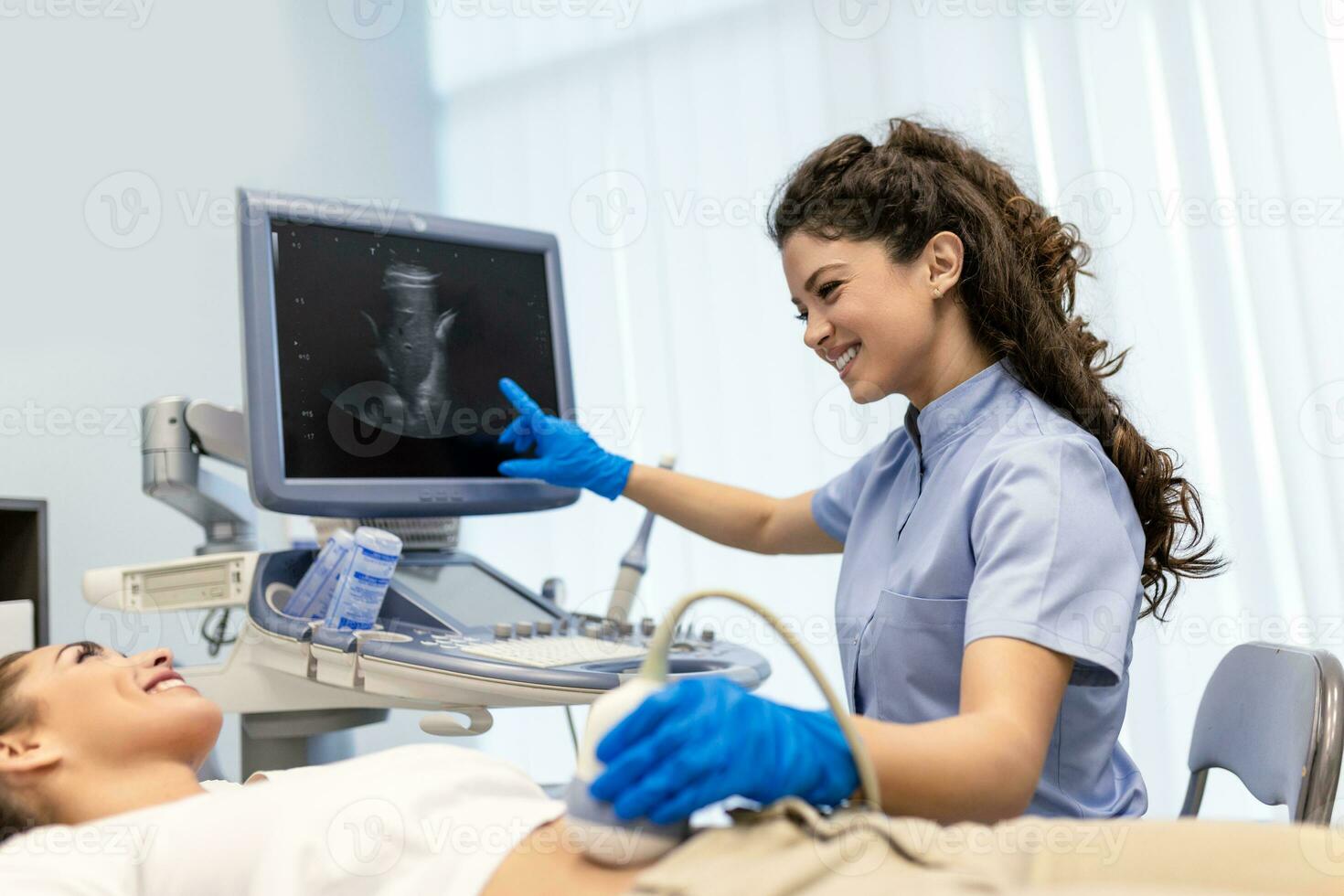 Ultrasound diagnostic of stomach on abdominal to woman in clinic, closeup view. Doctor runs ultrasound sensor over patient's girl tummy and looks at image on screen. Diagnosis of internal organs. photo