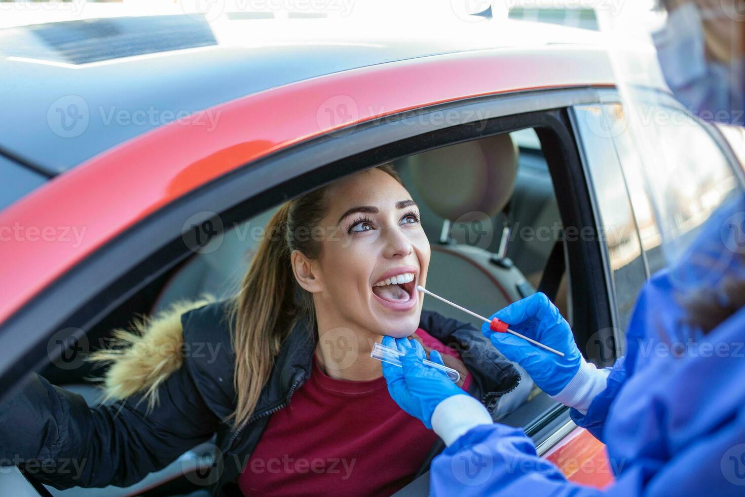 Medical worker wearing personal PPE surgical gloves and protective clothing, holding nasal swab, performing drive-thru COVID-19 testing, point of care on site location for PCR detection of Coronavirus photo