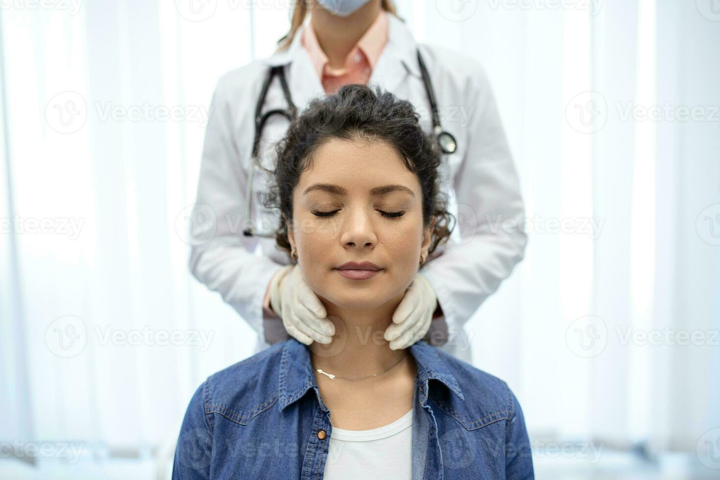 Endocrinologist examining throat of young woman in clinic. Women with thyroid gland test . Endocrinology, hormones and treatment. Inflammation of the sore throat photo
