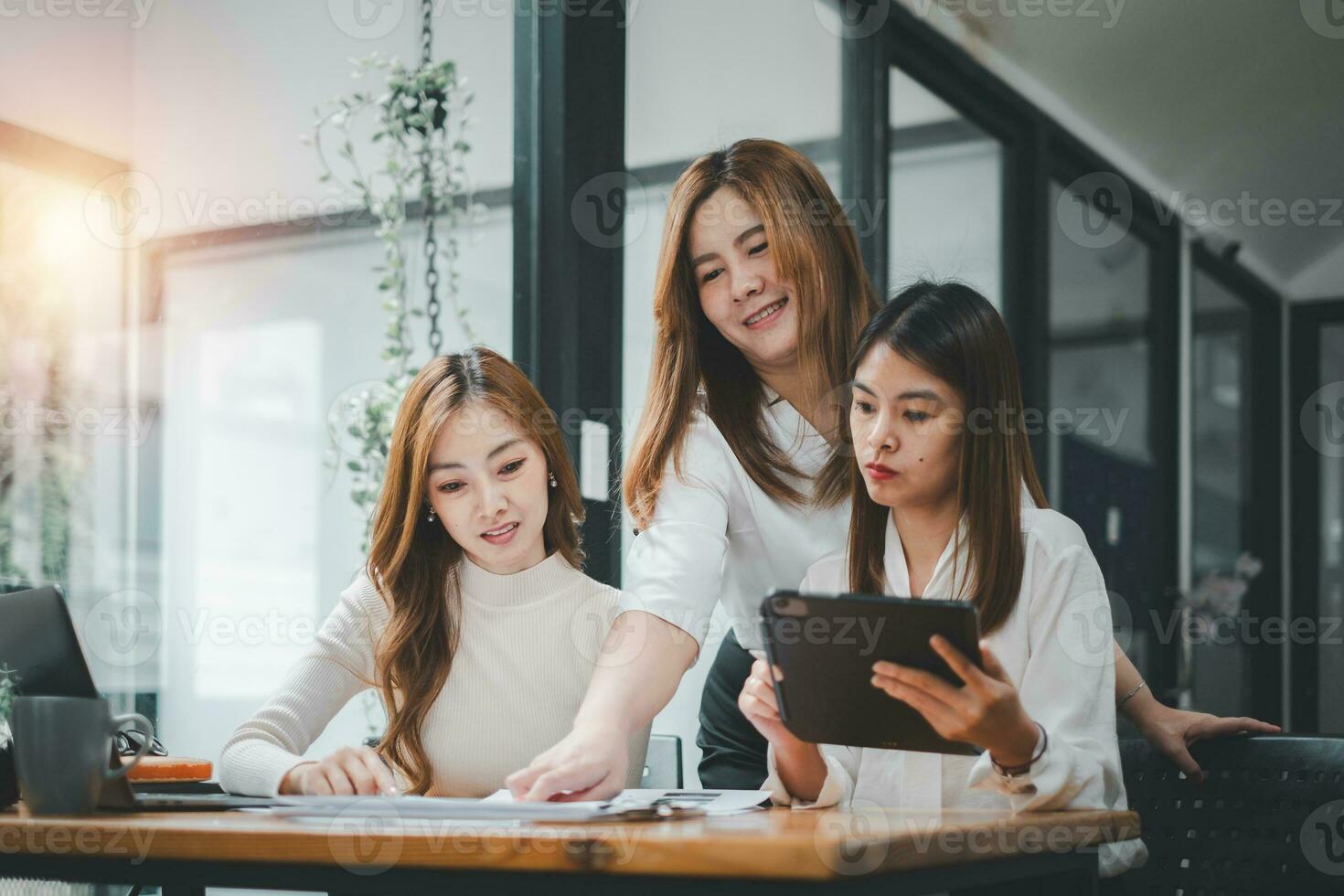 Three women analyzing documents while sitting on a table in office. Woman executives at work in office discussing some paperwork. photo