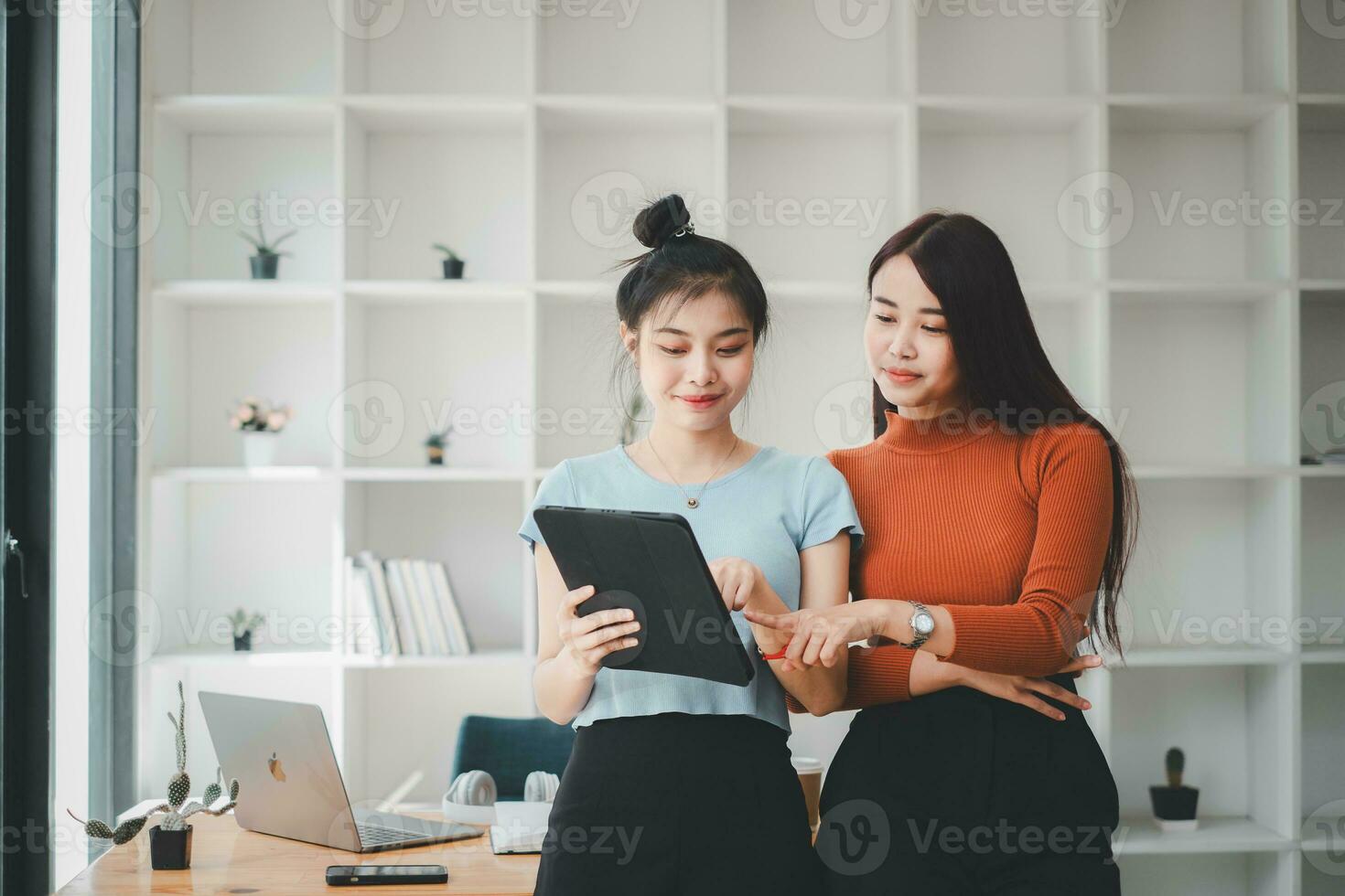 dos alegre joven multinacional colegas hablando mientras en pie en oficina con digital tableta, negocio concepto. foto