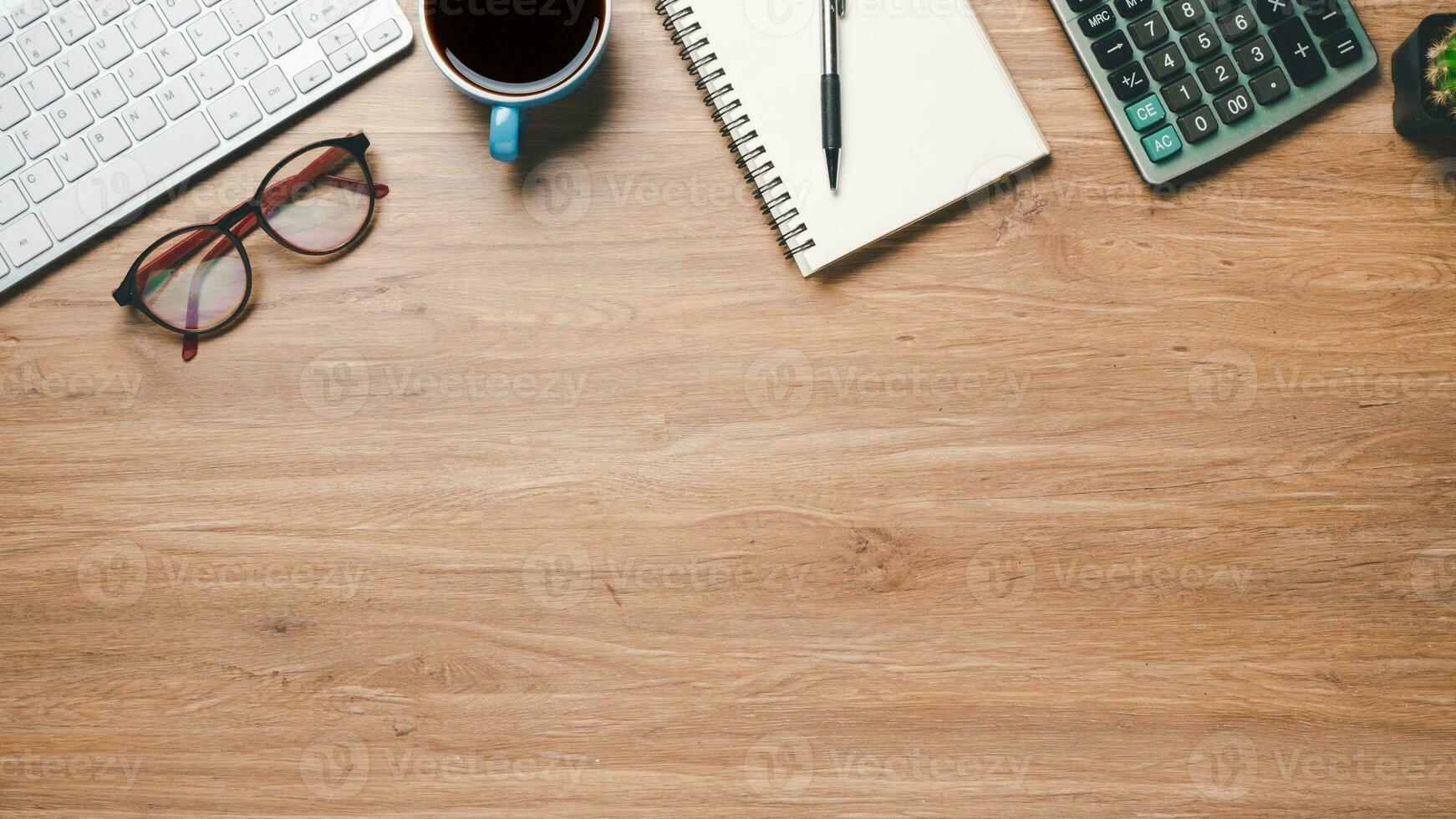 Top view, Office wooden desk with keyboard, notebook, pen, eyeglass, calculator and cup of coffee, copy space, Mock up. photo