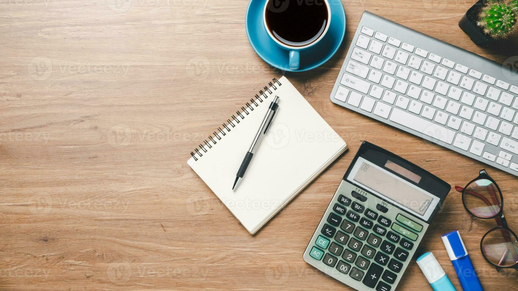 Top view, Office wooden desk with keyboard, notebook, pen, eyeglass, calculator and cup of coffee, copy space, Mock up. photo