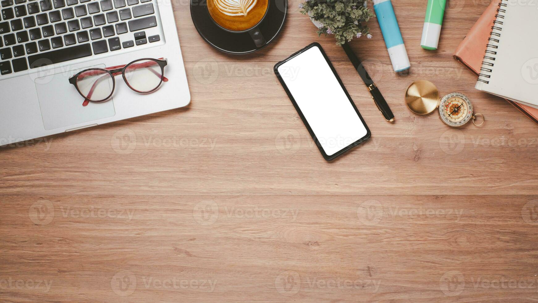 Wooden desk workplace with blank screen smartphone for product display, laptop, eyeglass, notebook, pen and cup of coffee, Top view flat lay with copy space. photo