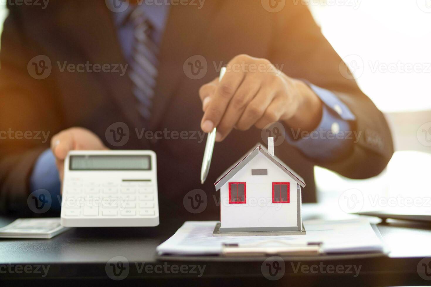 The real estate agent is reviewing the documents and calculating the interest rate to inform the tenant of the monthly installments to be paid before the real estate purchase agreement is finalized. photo