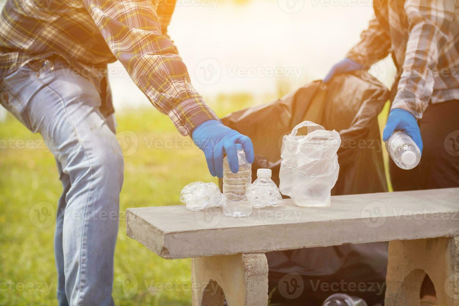 men collect plastic bottles on lawns and walkways in park and put them in bags to help keep them clean They can also collect plastic bottles for recycling. reducing environmental problems by recycling photo