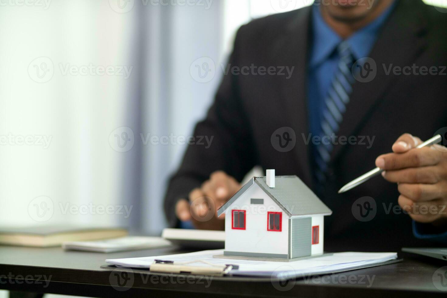 The real estate agent is reviewing the documents and calculating the interest rate to inform the tenant of the monthly installments to be paid before the real estate purchase agreement is finalized. photo