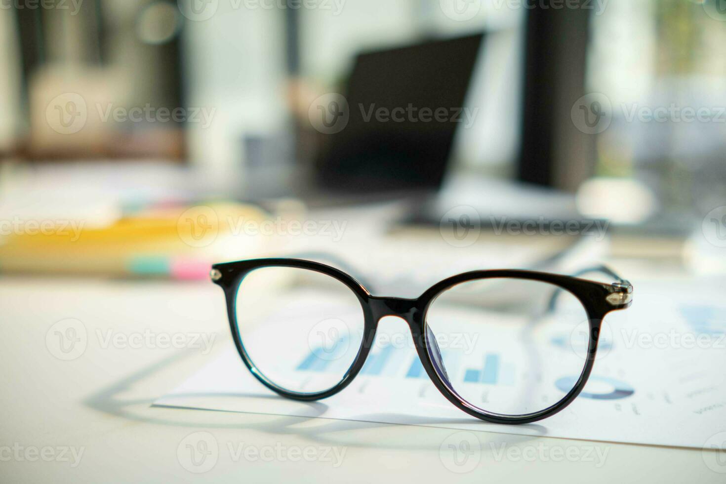 eye glasses placed on the desk are eye glasses that are prepared for people with farsightedness to work and read documents clearly. The concept of wearing eye glasses for normal vision photo
