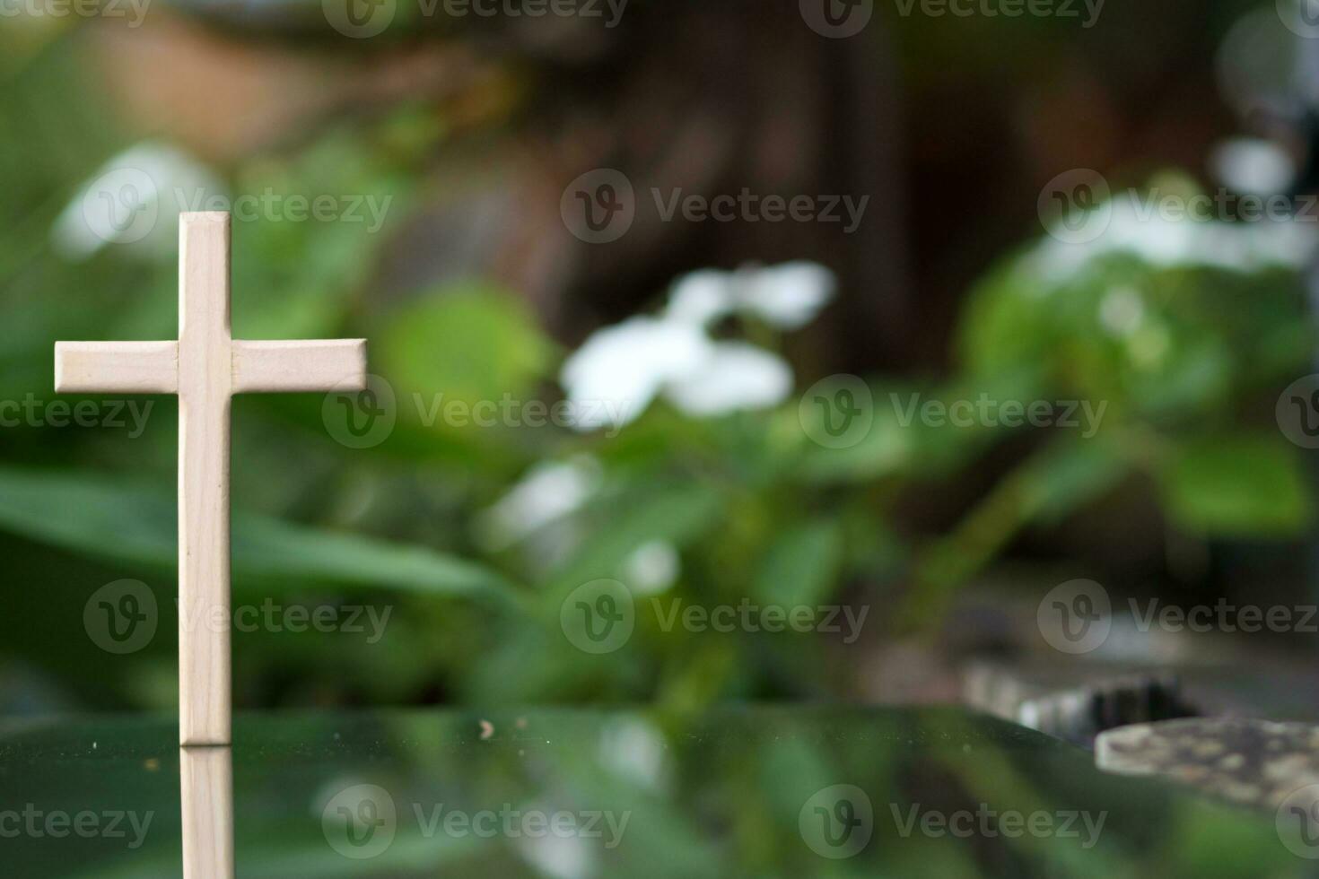 cross representing God in Christianity is placed on mirror and its reflection can be seen on blurred background of nature. cross on background is blurred and there is Copy Space on side for text. photo