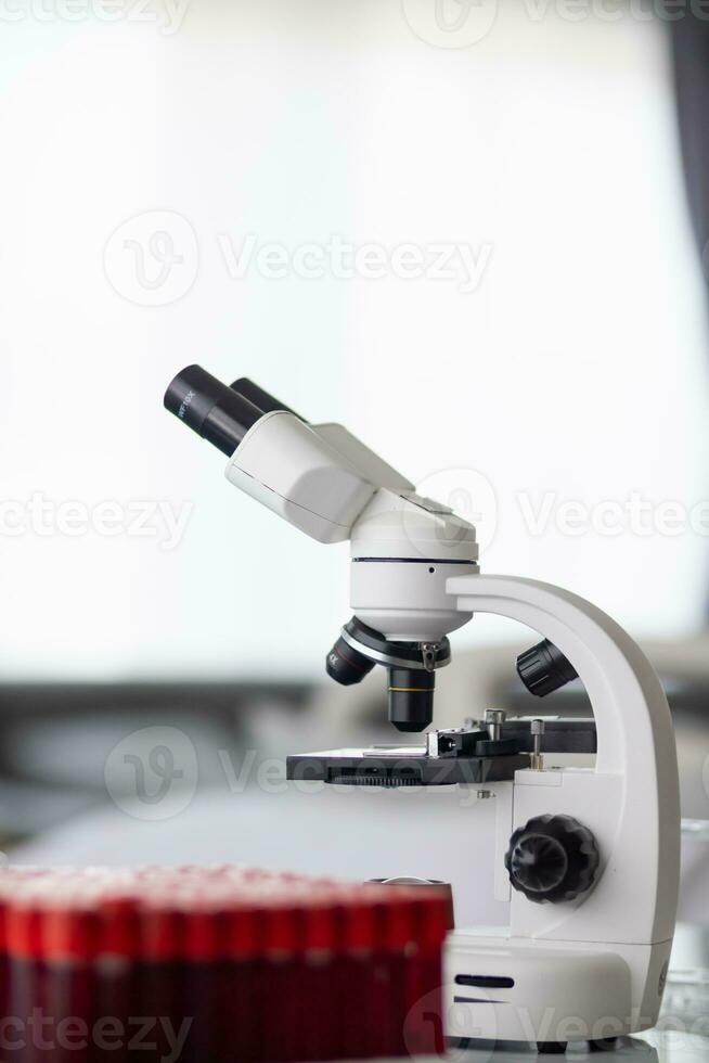 Test tubes and microscope are placed on white table in  lab to prepare virologists who want to use lab to examine samples of virus they received from epidemic. Medical equipment for use in laboratorie photo