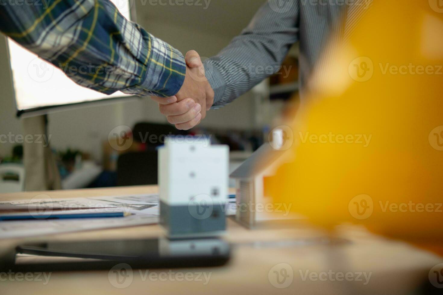 construction engineer joins hands with architect to congratulate housing project that architect team has designed and has been accepted by engineering team. concept of handshake for congratulations photo