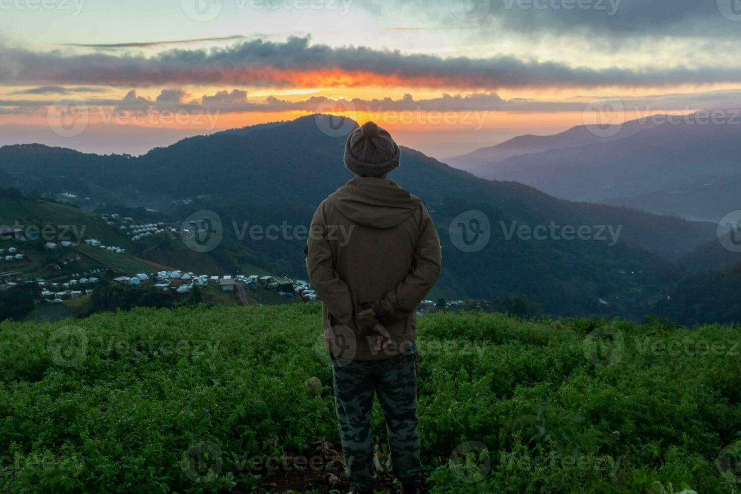 Male tourists stand on top of a mountain in the morning looking at the beautiful view of the twilight as the sun rises on the horizon and praying to God for blessings according to the Christian faith. photo