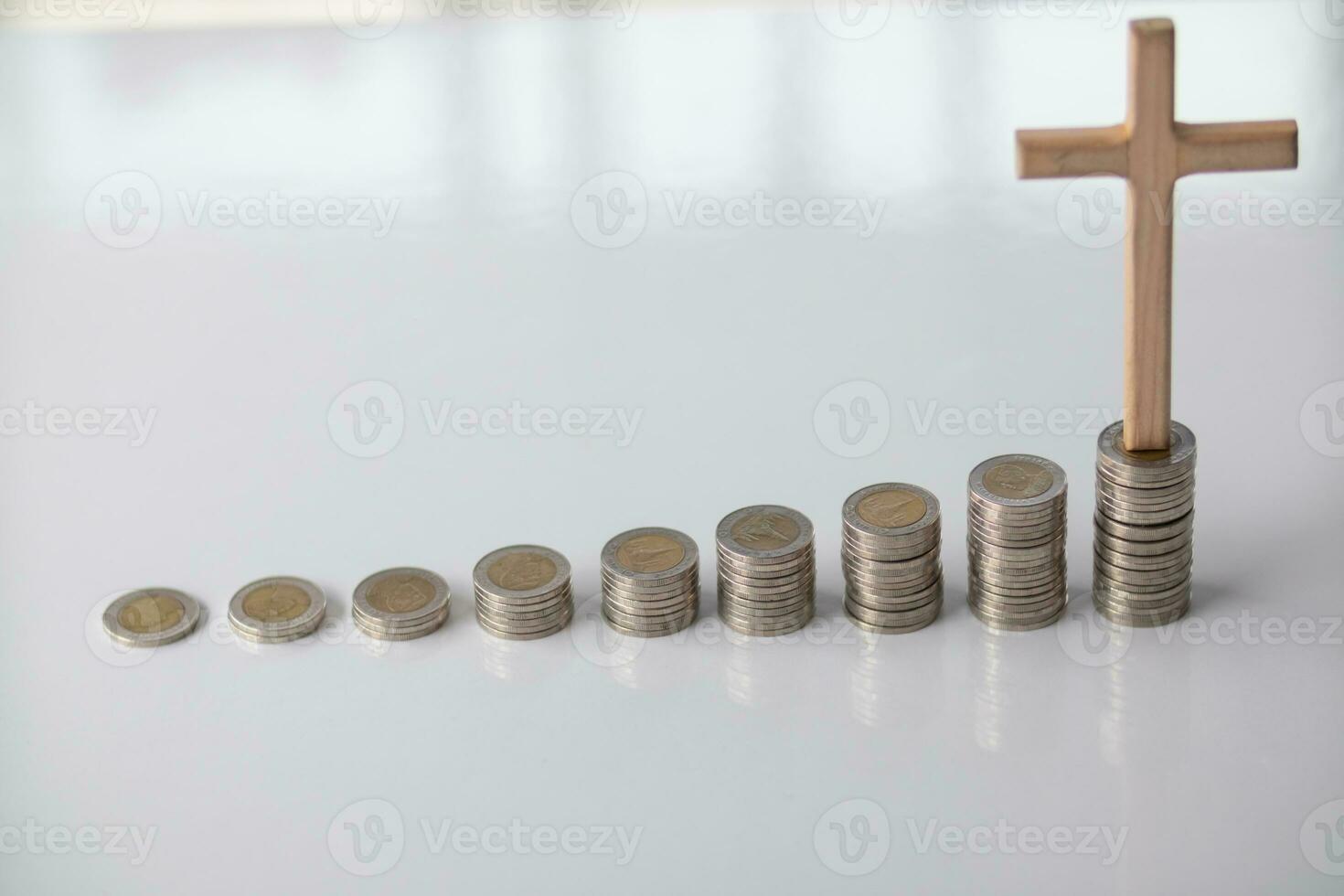 ascending pile of coins with a cross on top is the concept of life insurance for health care and accumulation of benefits for the family after death. The concept of health insurance and life insurance photo