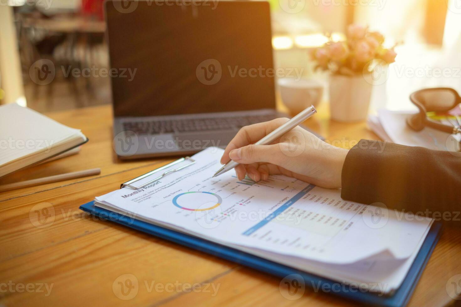 A young businesswoman is reviewing documents and their information to compile statistics and summarize annual results. The concept of reviewing annual turnover data from a collection of documents. photo
