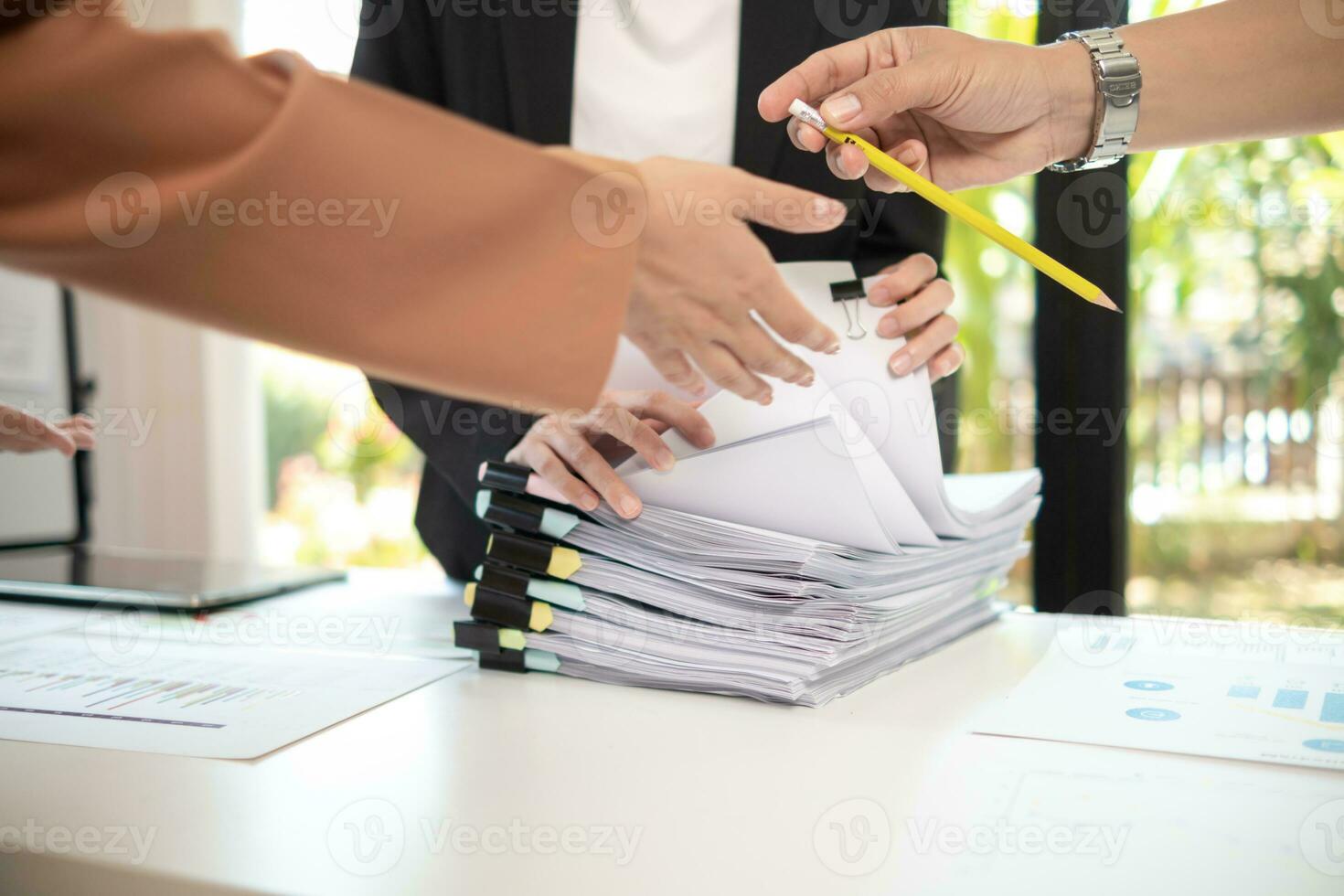 secretary searches through stacked paperwork on desk in office to find lease within stacked paperwork just before meeting. concept difficulty in finding hire purchase contract from stacked paperwork photo