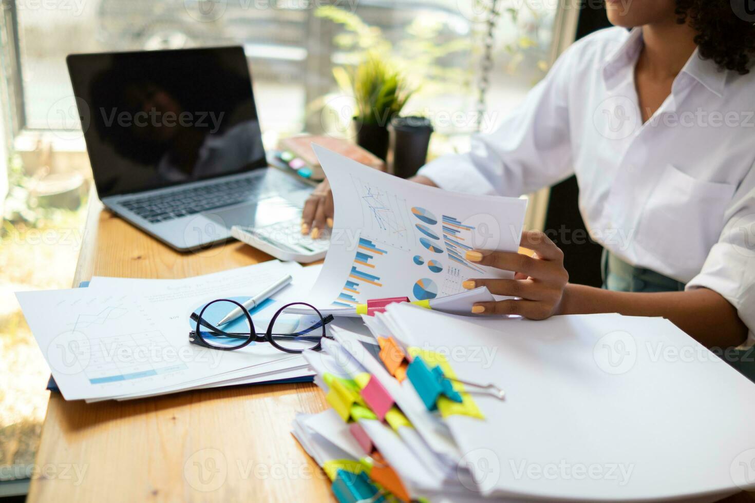 secretary searches through stacked documents on desk in office to find lease within stacked documents just before meeting. concept difficulty in finding hire purchase contract from stacked documents photo