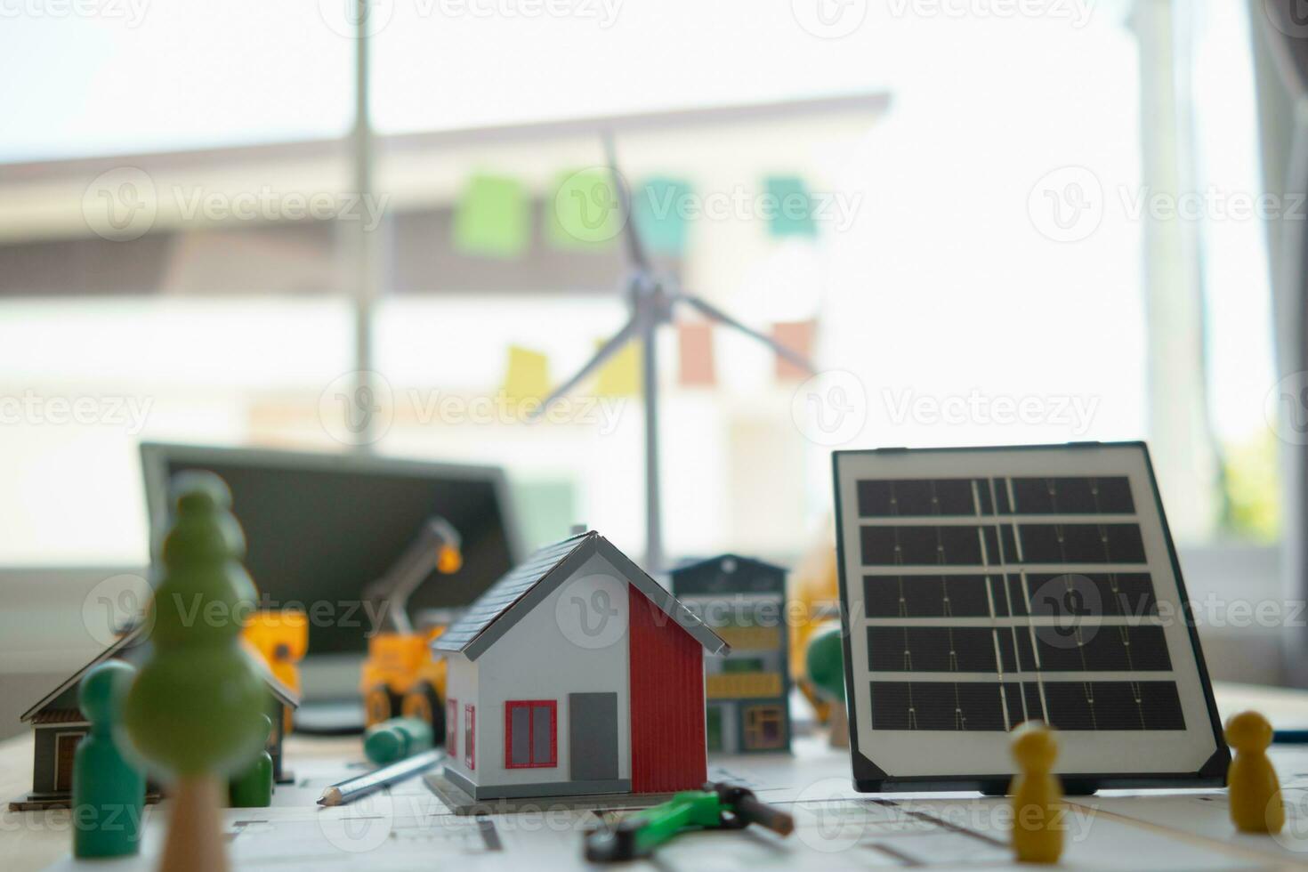 On desk of engineers lay model of house And solar panels to use in planning installation of solar panels to  house in order to get most cost effective energy from installing solar panels. photo