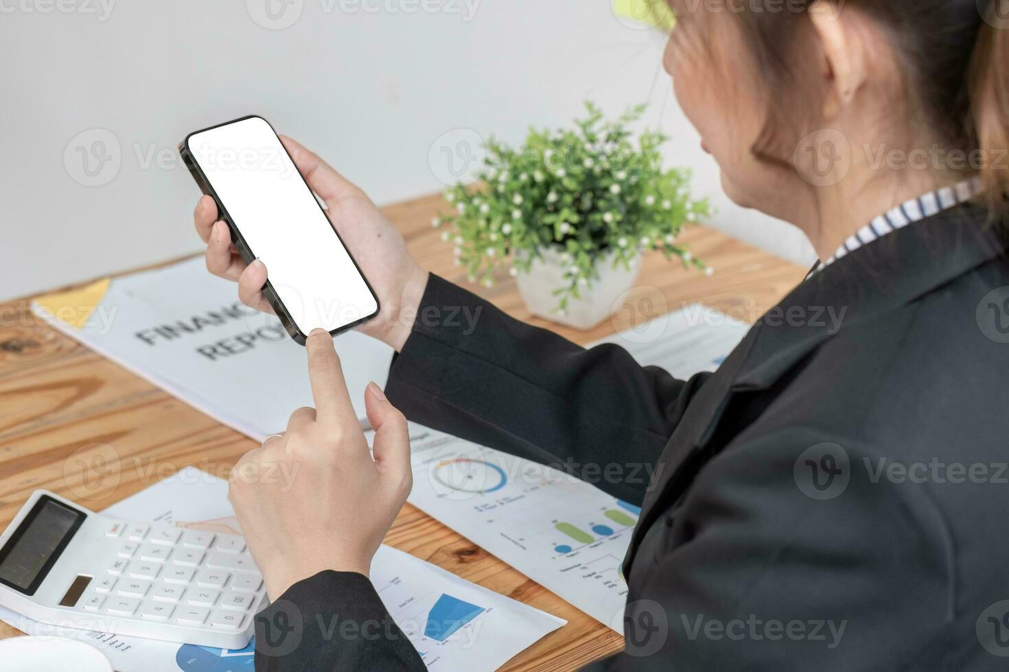 Woman holding phone showing white screen on top view while sitting in office photo