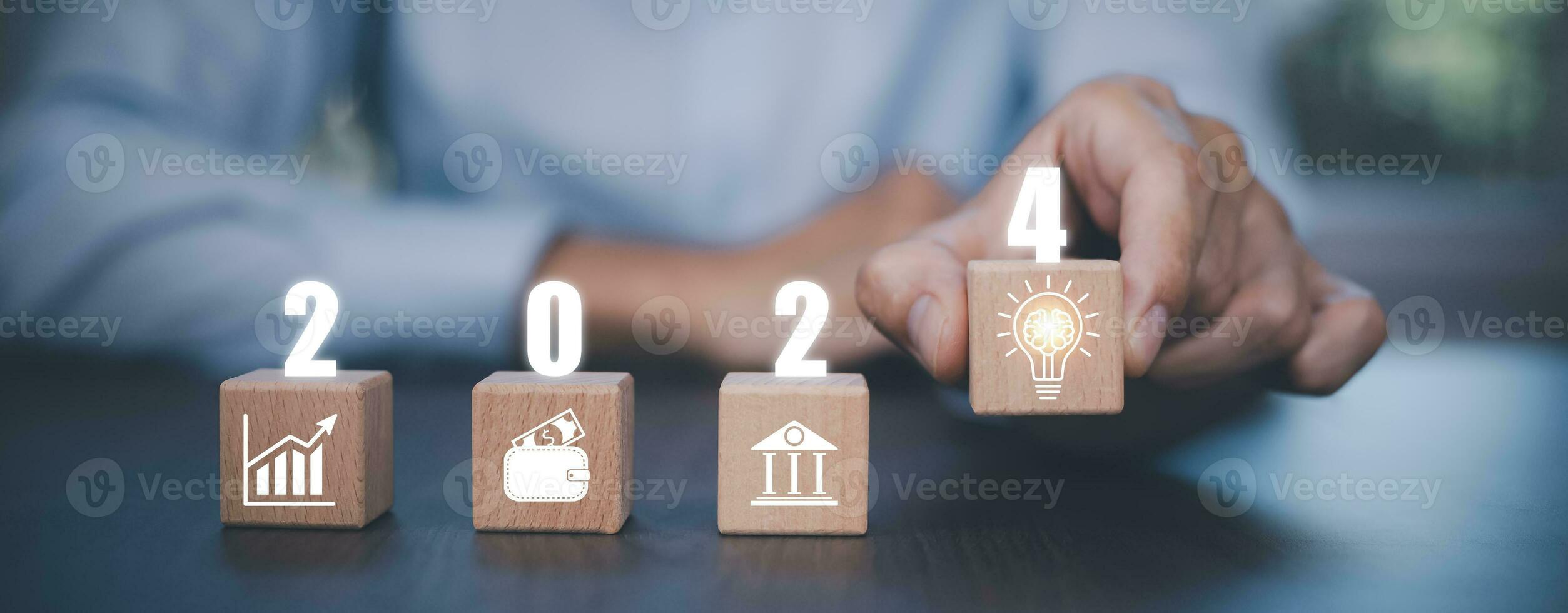 Concept 2024, Businessman touch square wood and icon on office background, Money spending planning, plant growing up on coins and investment budget, Save money for prepare in the future, new year photo