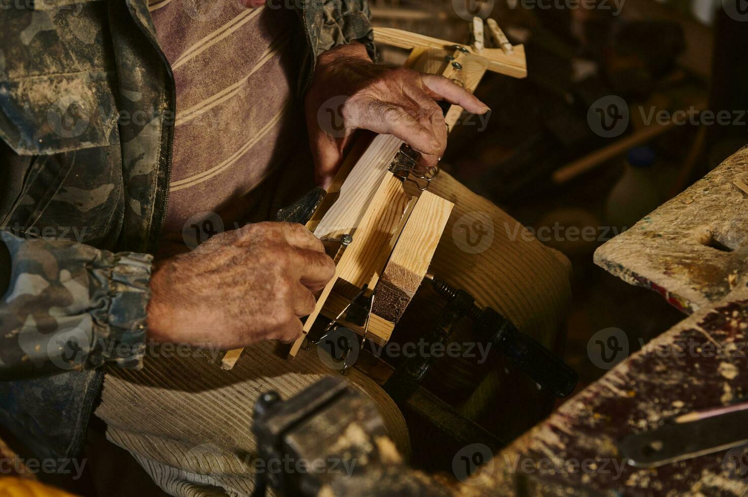 Closeup of carpenter hands in work on a wooden items in workshop. photo