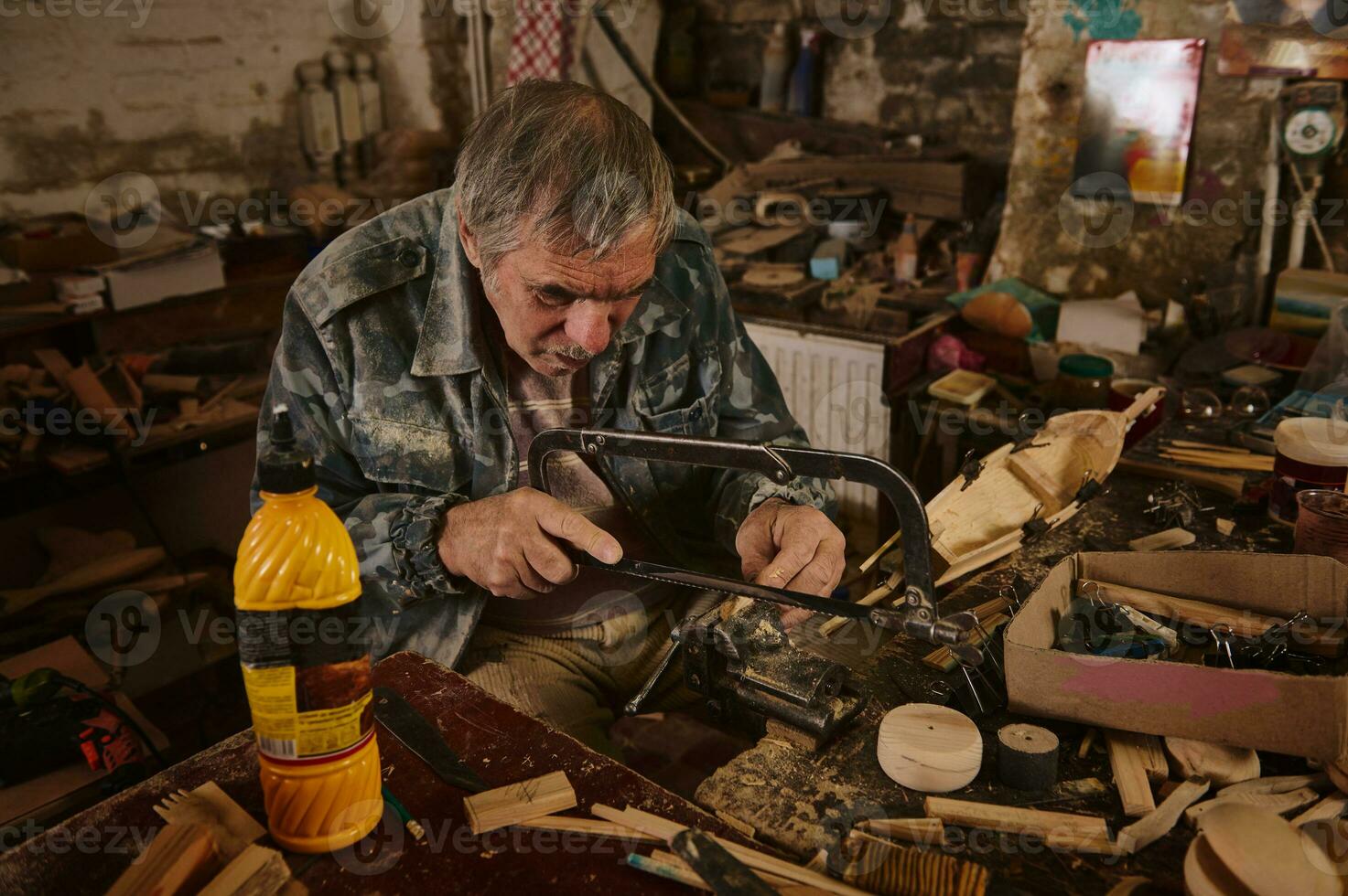 un maduro madera artesano sierras un pedazo de madera sujetado en un vicio con un sierra. artesano haciendo hecho a mano arte de madera juguetes carpintero en acción foto
