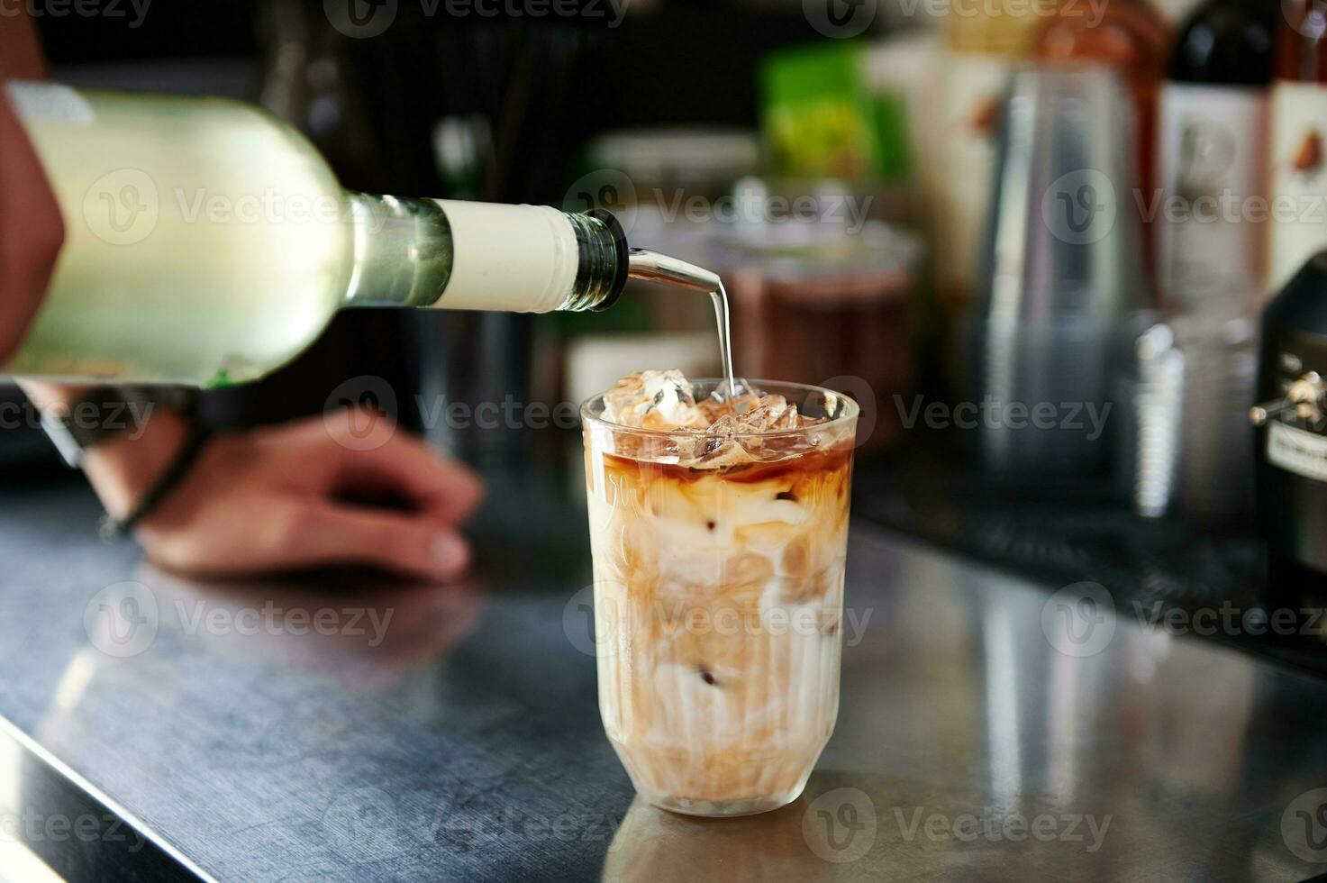 de cerca de barista torrencial un líquido cóctel dentro un vaso con bebida mientras preparando un refrescante cafeinado con hielo bebida foto