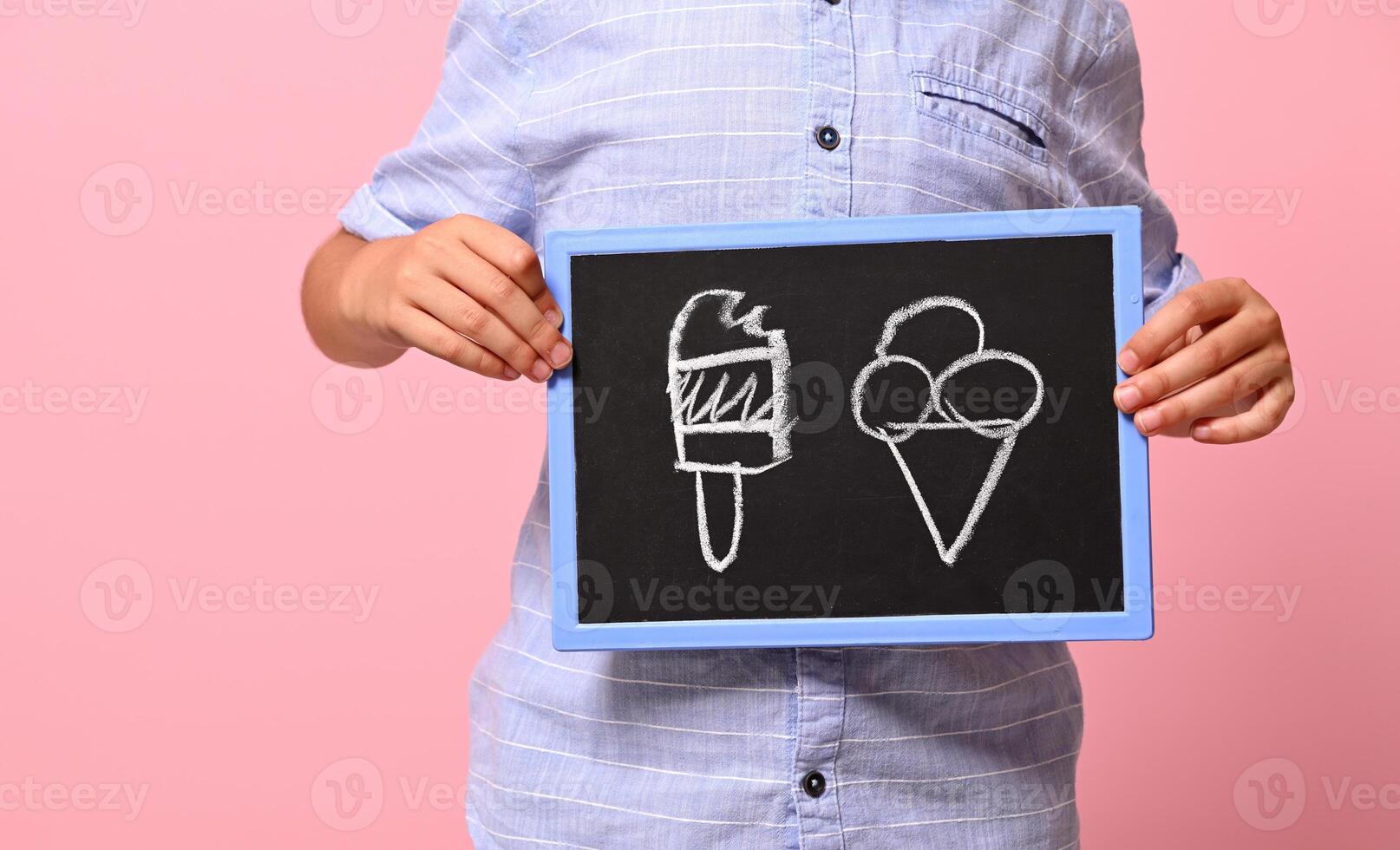 Cropped view of a boy hands holding a chalkboard with drawn ice cream against pink background with copy space photo