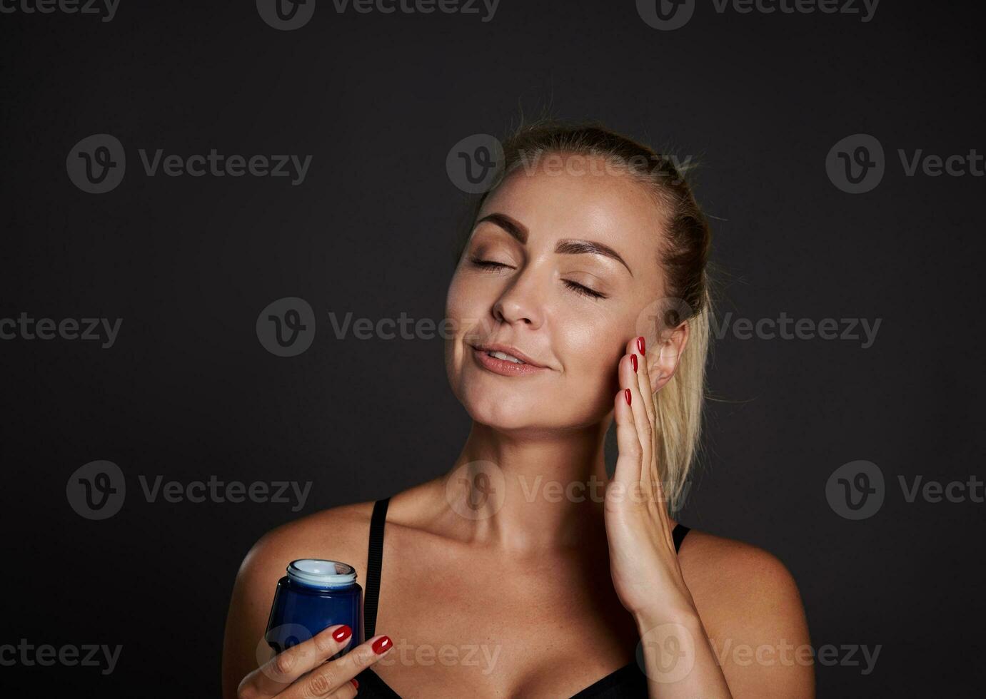 Closeup beauty portrait stunning beautiful middle aged woman applying face moisturizer, smoothing serum, taking care of facial skin. Cosmetic procedures against wrinkles, spa, wellness, youth concept photo