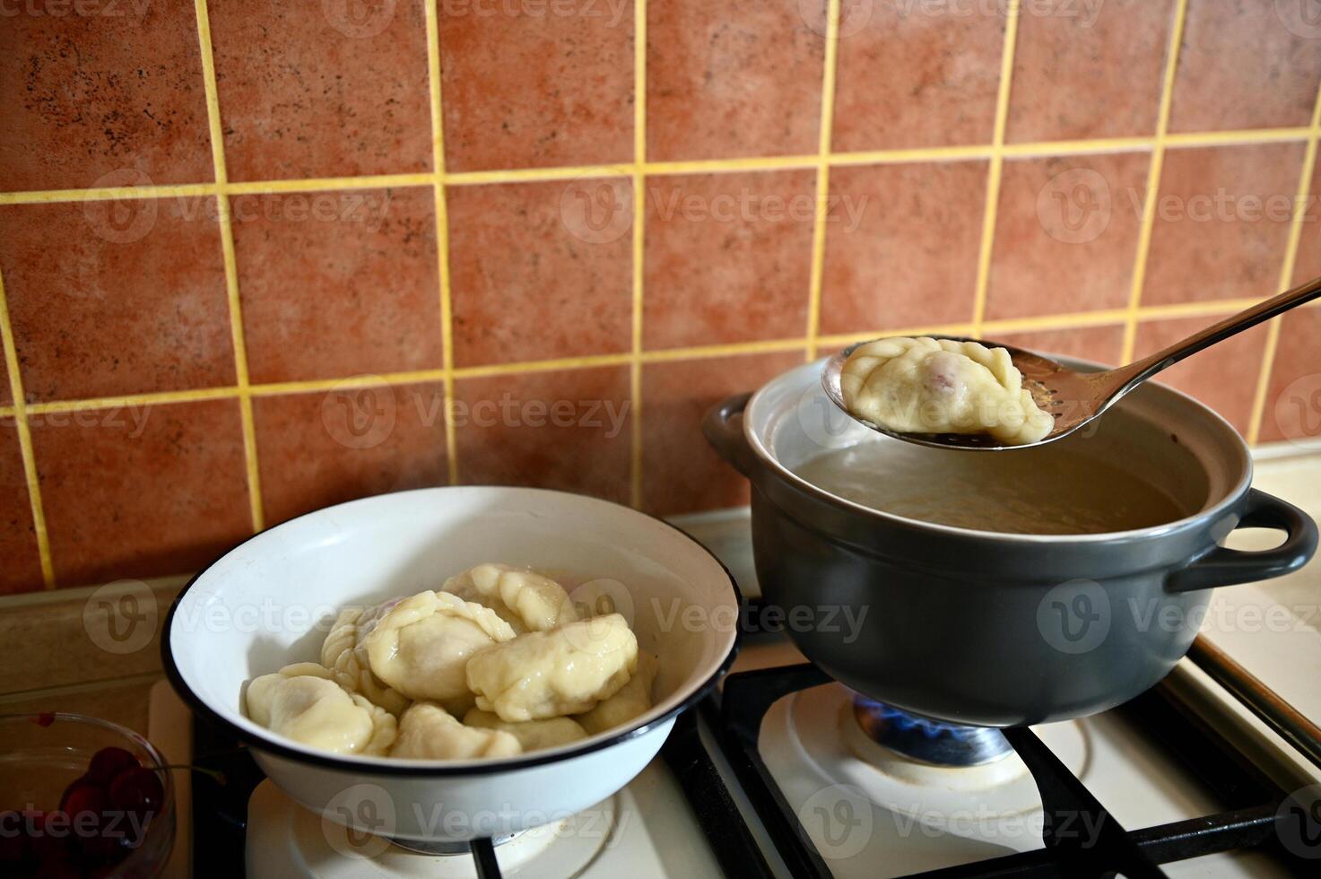 The pastry chef takes out cooked dumplings from boiling water into a colander. Process of cooking dumplings step by step. Close-up, food background. photo