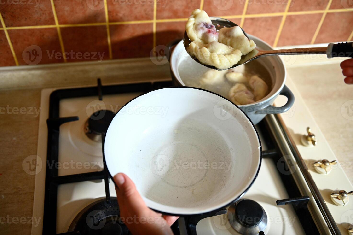 High angle view of a pastry chef takes out cooked dumplings from boiling water into a colander photo