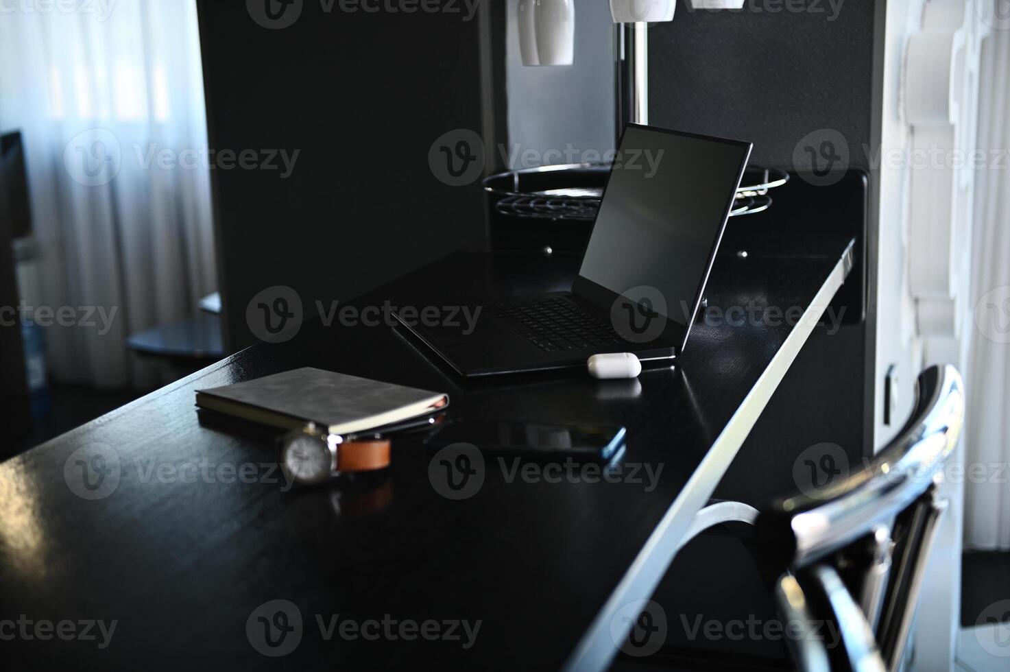 Office accessories, stationery, laptop, earphones on the box, watch, mobile phone and gray notepad on wooden table at home kitchen photo