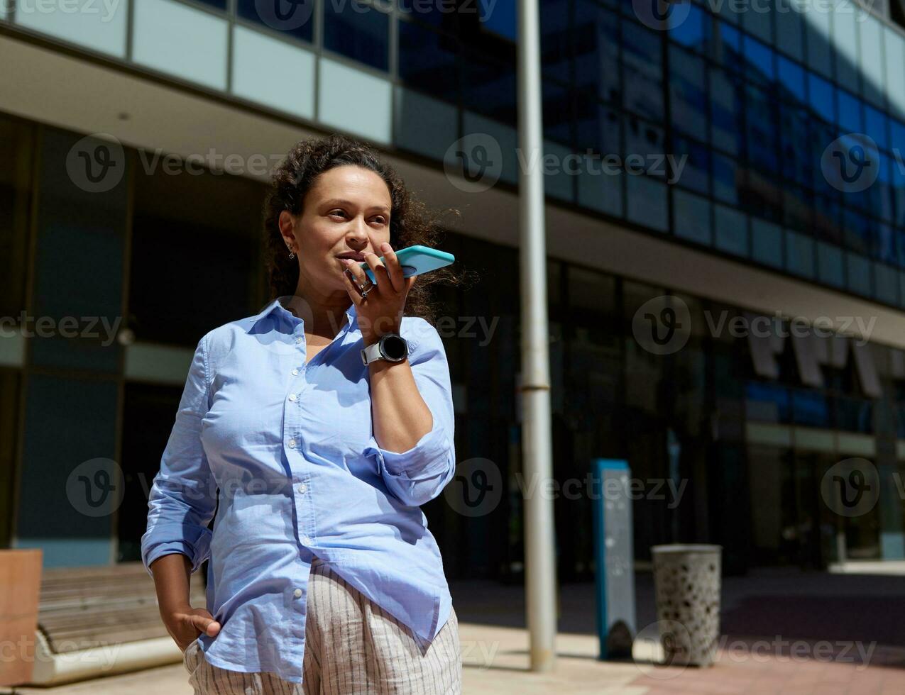 Confident purposeful businesswoman, entrepreneur using mobile phone, recording a voice message photo