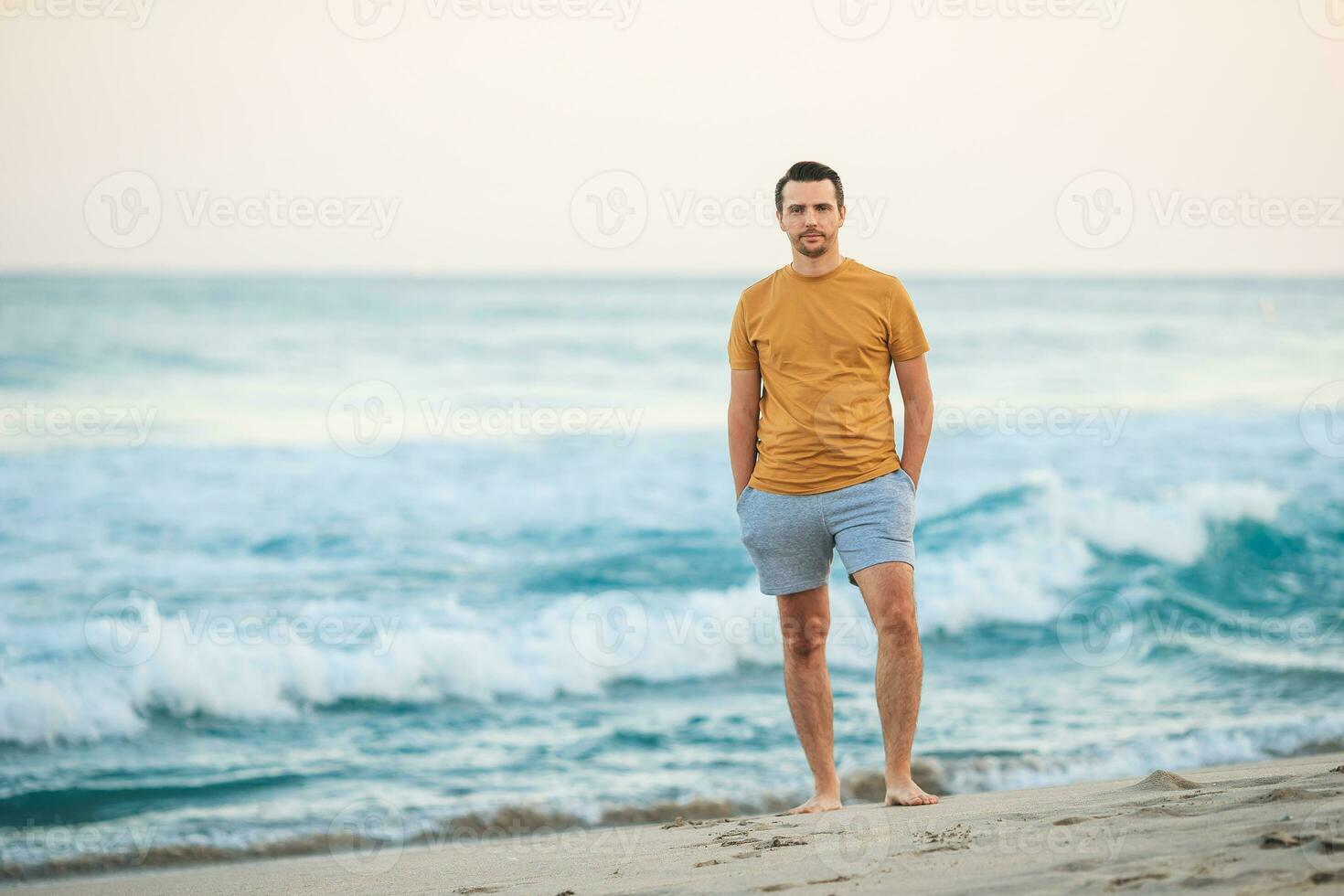 Young man walking on the beach at sunset photo