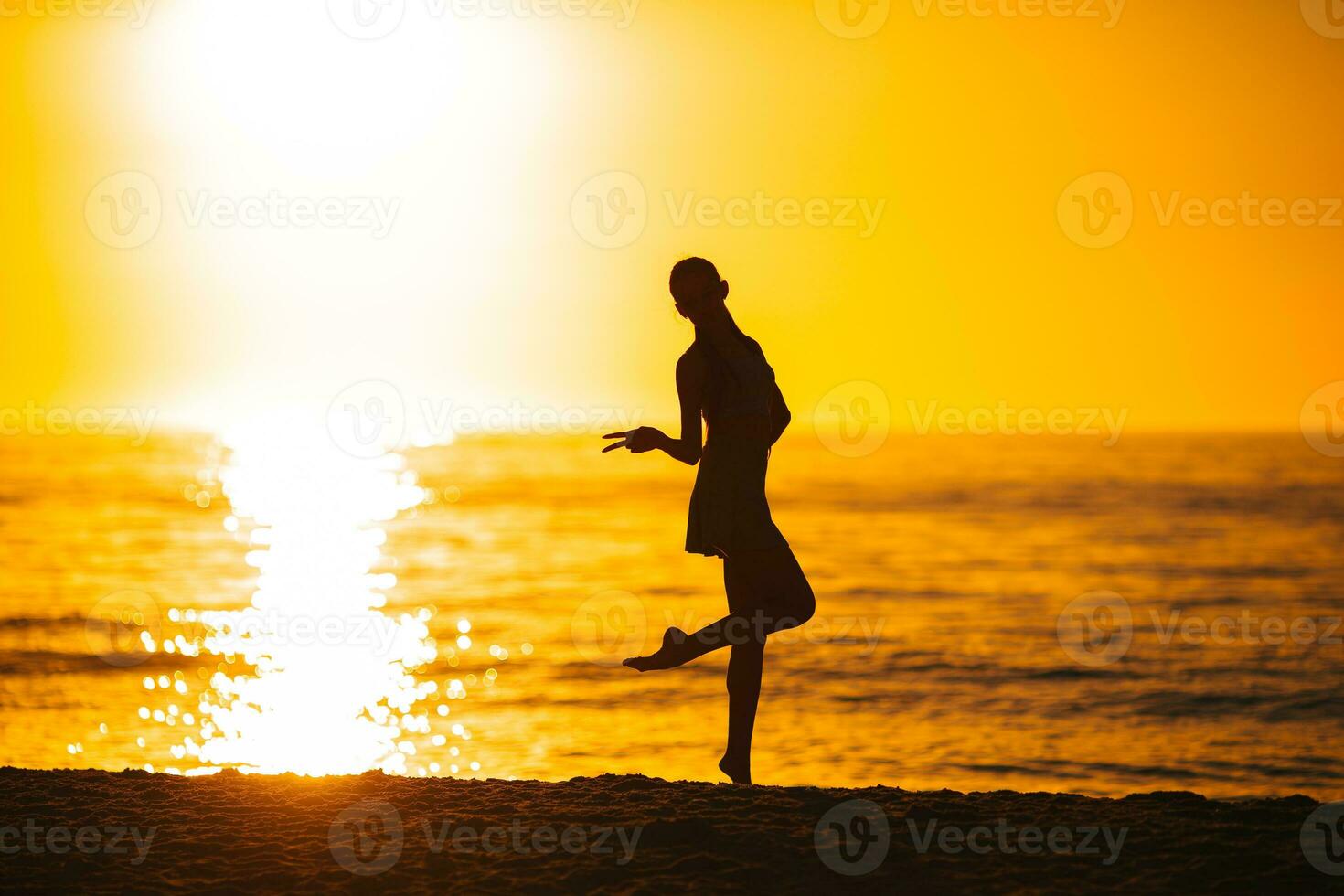 silueta de la hermosa chica disfrutando de la hermosa puesta de sol en la playa foto