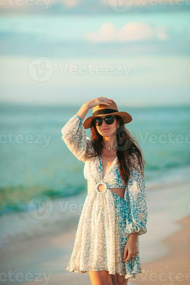 Young beautiful woman at straw hat on the beach at sunset photo