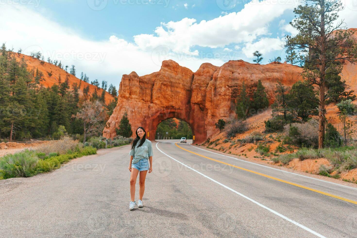 Young happy woman in background of natural stone arch Bridge in the Red Canyon National Park in Utah, USA photo