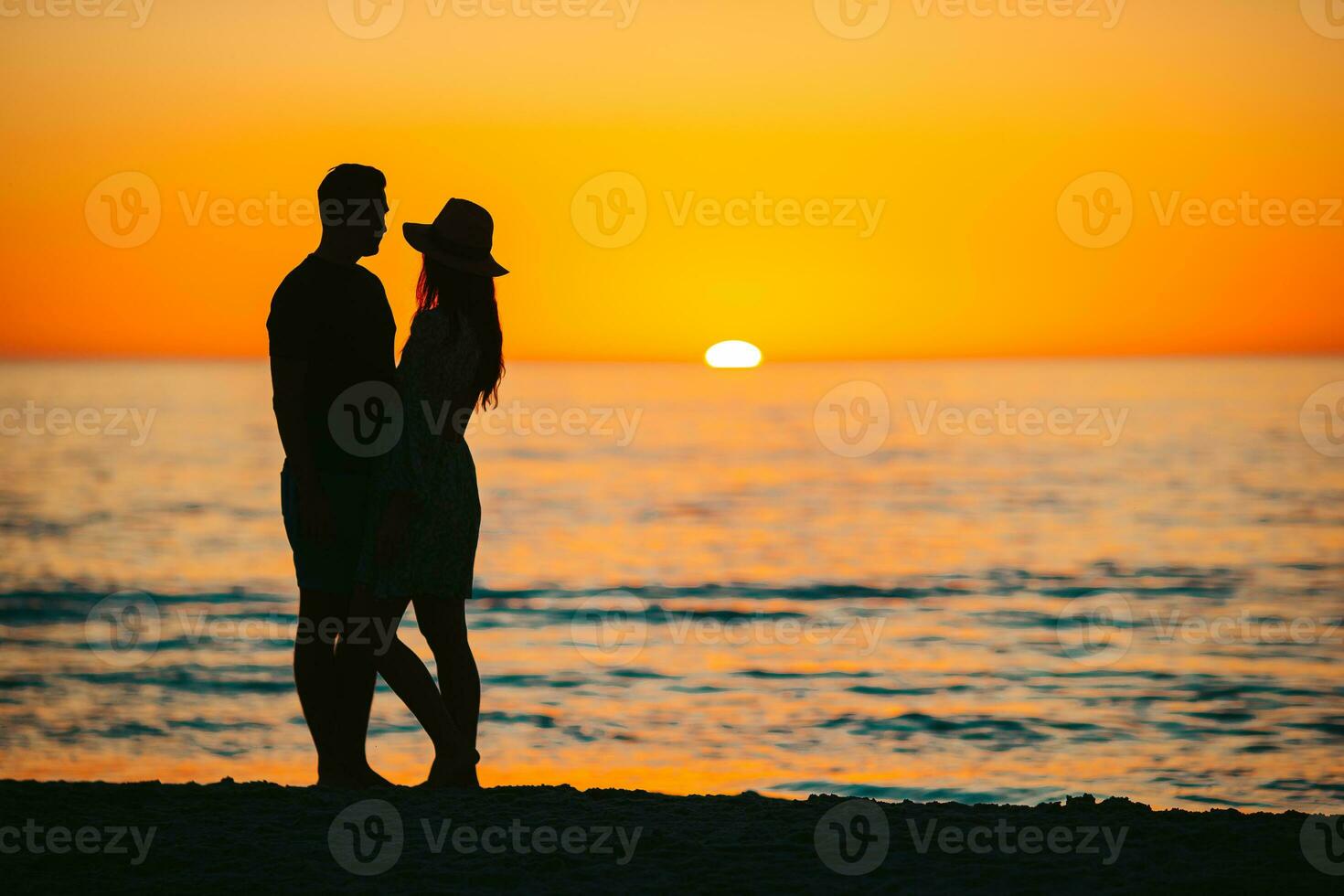 Happy couple on the beach at beautiful sunset on background photo