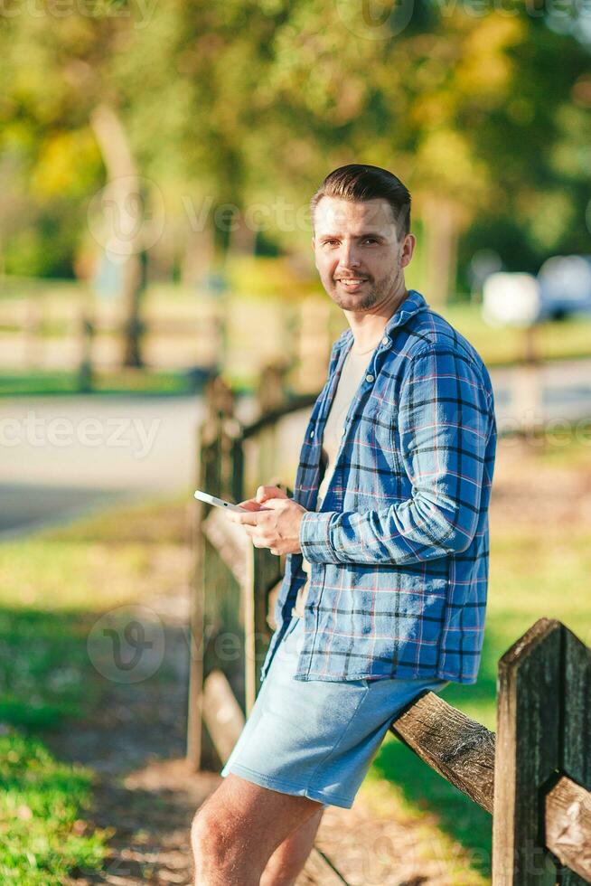 Portrait of young man with smart phone in the park looking at camera photo
