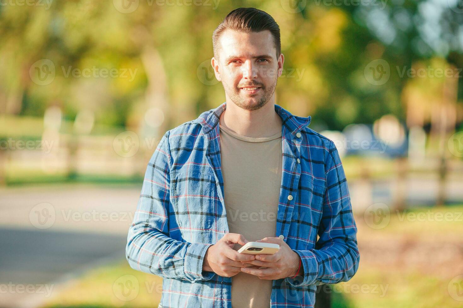 Young man using mobile phone outdoor in the park photo