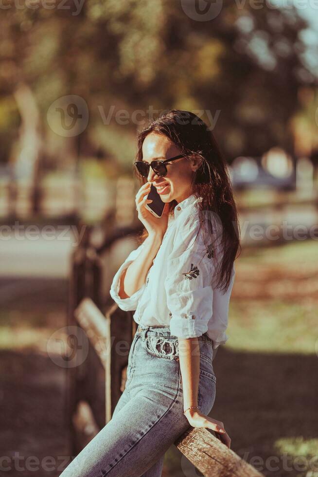 Young woman talking on the mobile phone outdoor in the park photo