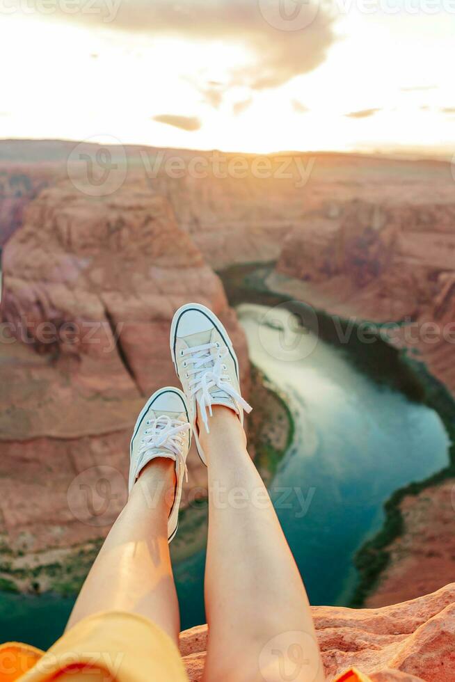 Legs on the edge of the cliff at Horseshoe Band Canyon in Page, Arizona. Adventure and tourism concept. Beautiful nature in USA photo