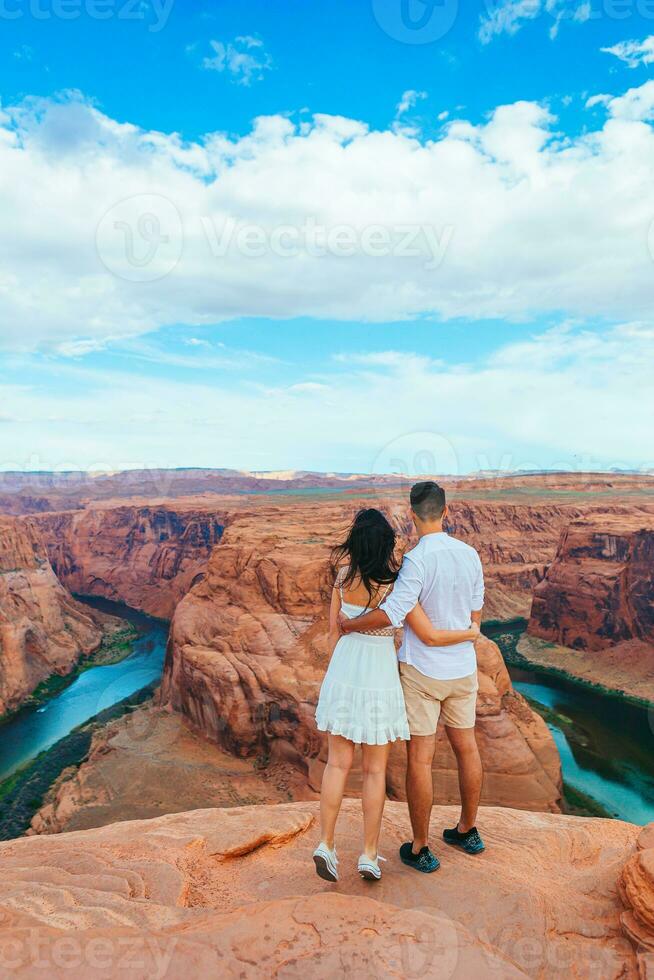 contento Pareja en el borde de el acantilado a herradura banda cañón en paje, Arizona. aventuras y turismo concepto. hermosa naturaleza en Estados Unidos foto