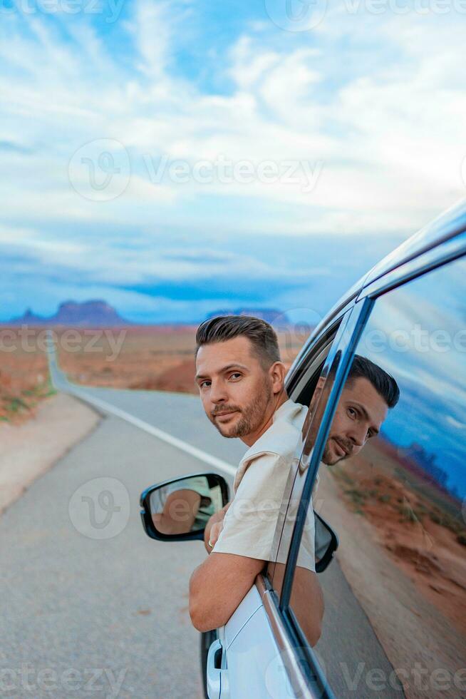 joven hombre viaje por coche en famoso Monumento Valle en Utah foto