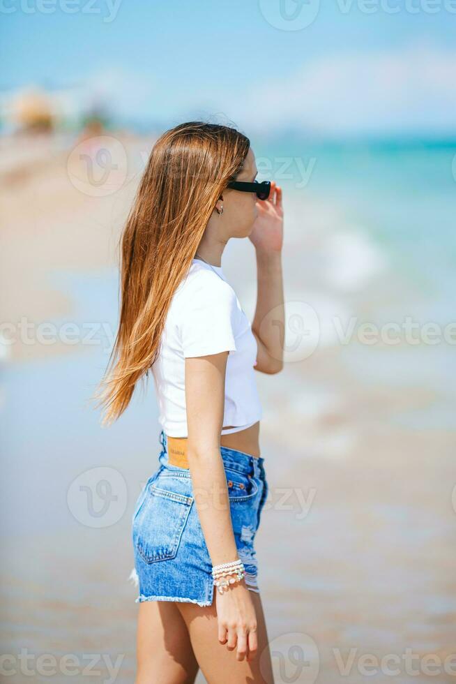 linda pequeño niña a playa durante caribe vacaciones salpicaduras foto