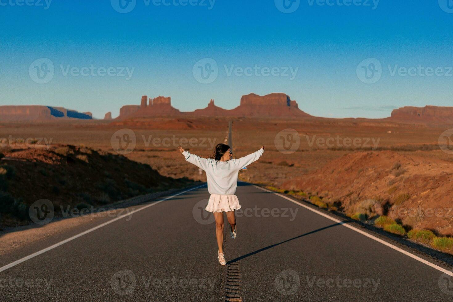 Happy young woman in white dress on the famous road to Monument Valley in Utah. Amazing view of the Monument valley. photo