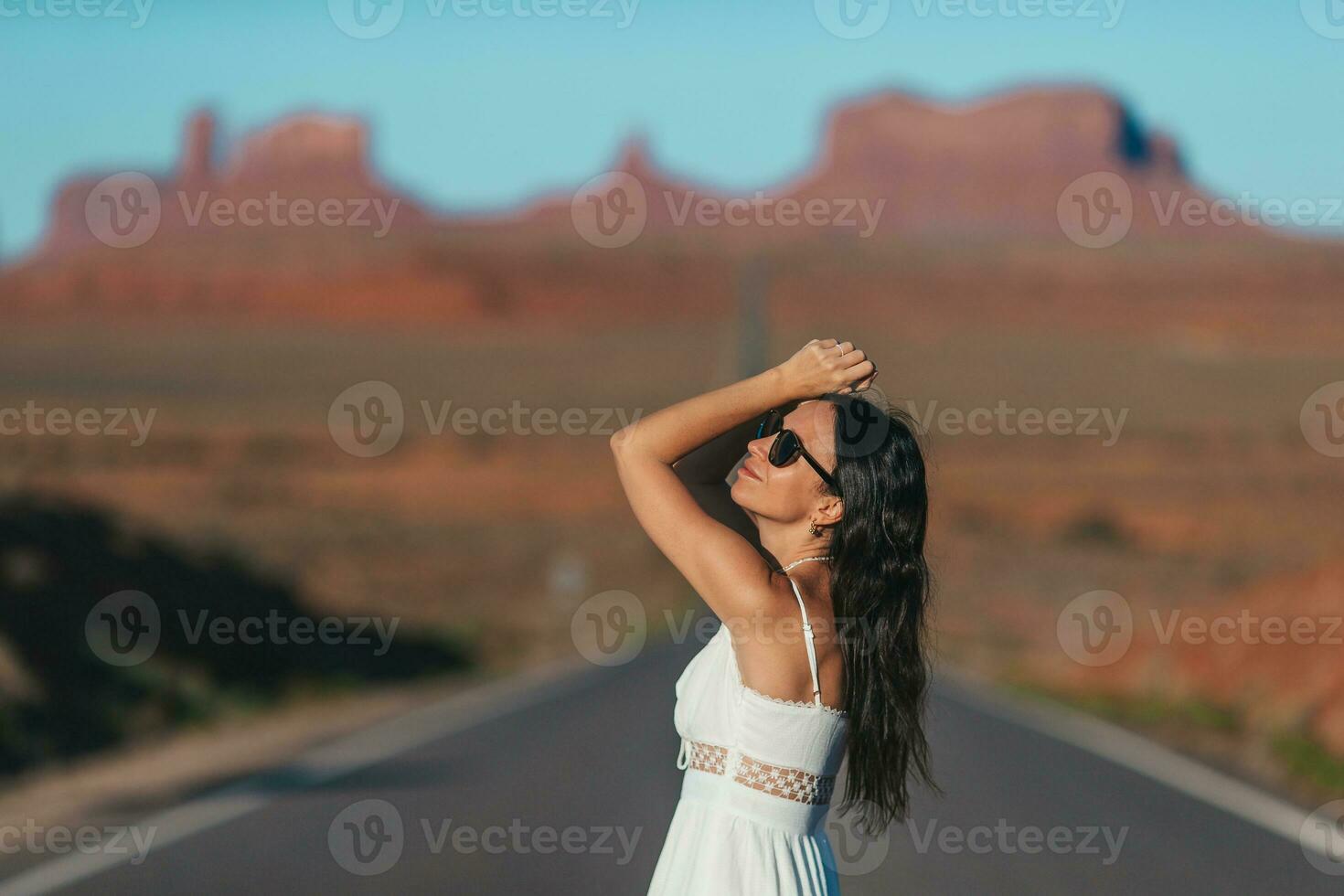Happy young woman in white dress on the famous road to Monument Valley in Utah. Amazing view of the Monument valley. photo