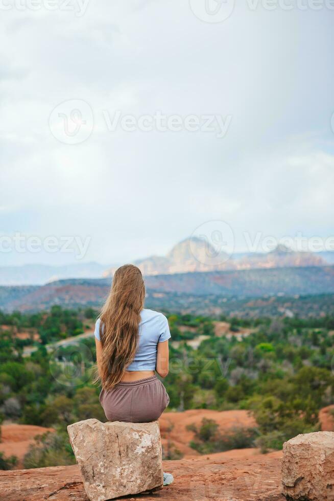 niña disfruta el ver de el sedona paisaje desde el parte superior de el campana rock excursionismo camino, famoso para sus muchos energía vórtices y rojo rocas foto